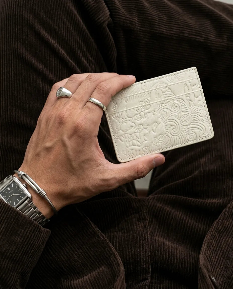 Bone shishi embossed card holder, held in hand